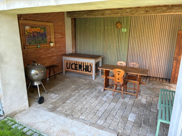 Svatební kavárnička U Cerhů – zastřešená terasa s dřevěným nábytkem, grillem a logem U Cerhů v historickém statku Kněžmost